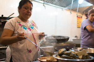 La Morada owner Natalia Mendez, 44, spoons mole blanco sauce over a roasted poblano pepper. 