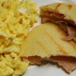 An arepa sliced in half, filled with deli turkey slices and served with scrambled eggs for breakfast. Photo: Alexandra Torrealba.