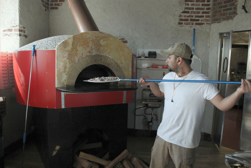 Salas Flores slides an unbaked pizza into the wood-burning oven at Acri Café in the Bronx. The restaurant recently opened in November of 2015. Photo: Kailyn Lamb.