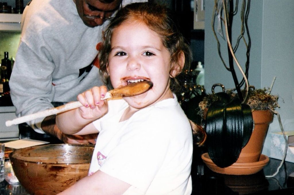 The writer as a child, licking the spoon after her mother, who took this photo, made chocolate mousse cake. Photo: Nina Friend